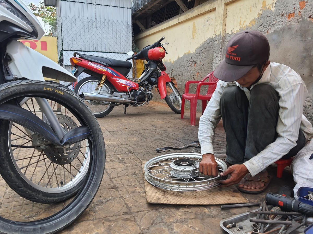 Anh Lợi làm nghề sửa, vá xe tranh thủ cho xong công việc.