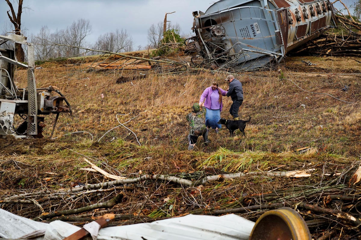 Cư dân địa phương chật vật đi qua đoàn tàu trật bánh ở Earlington, Kentucky. Ảnh Reuters.  