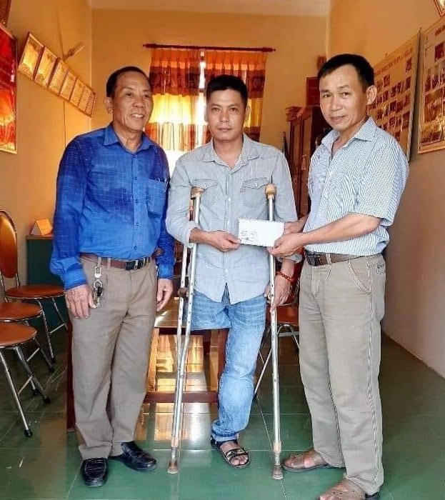 Ông Nguyễn Sỹ Nghị (ngoài cùng bên phải) trao quà cho anh Lê Văn Giang  để lắp chân giả.