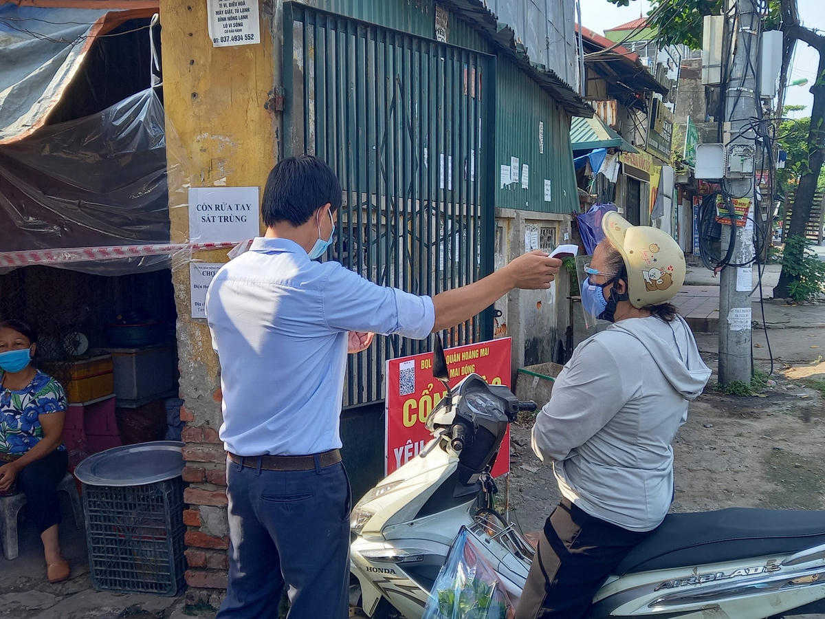 Tại khu vực chợ Mai Động, người dân đều được đo thân nhiệt, kiểm tra phiếu đi chợ trước khi vào chợ. 