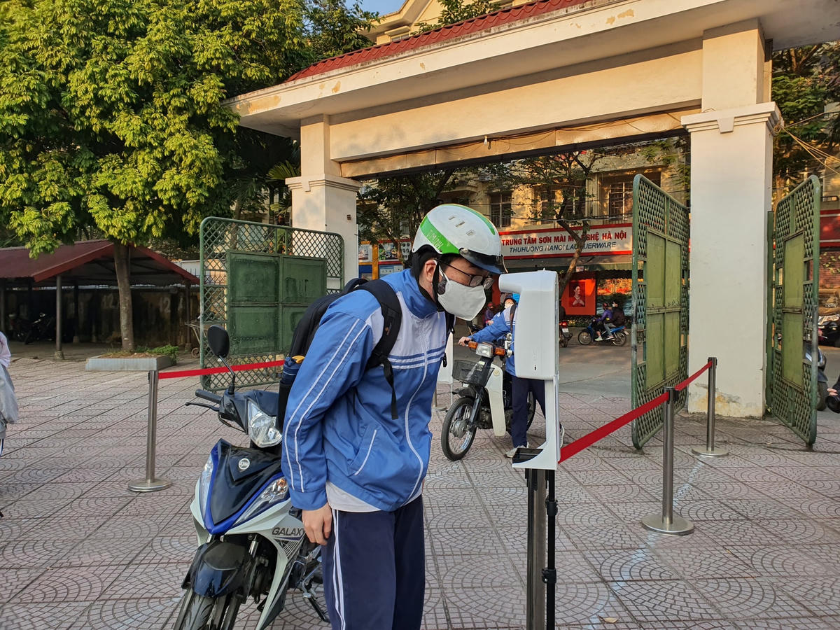 Học sinh Trường THPT Cầu Giấy xếp hàng giãn cách, đo thân nhiệt và sát khuẩn tay trước khi vào lớp học.