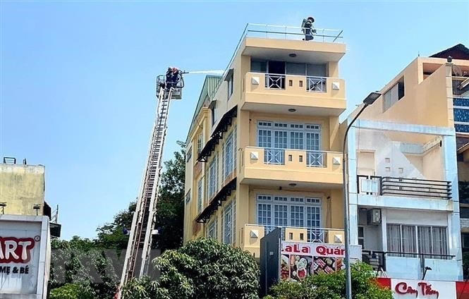 Cảnh sát chữa cháy tiếp cận từ nóc nhà để giải cứu 2 nạn nhân. Nguồn: TTXVN.