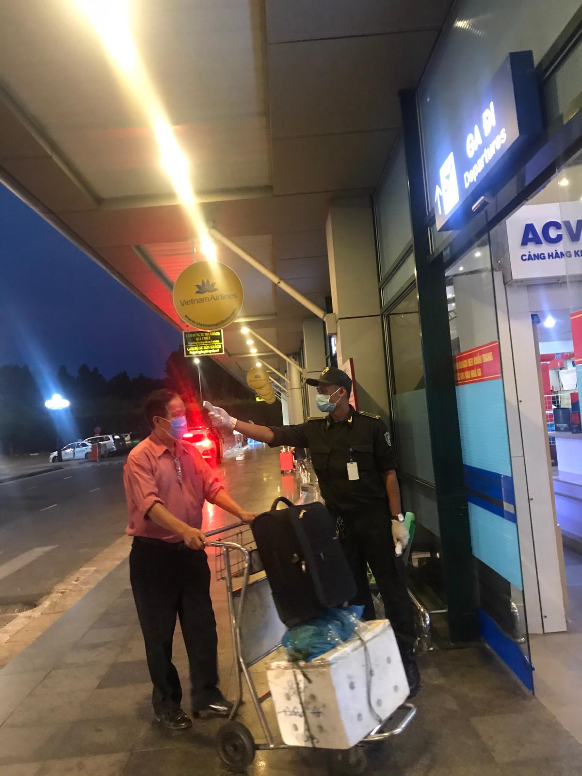 Nhân viên an ninh sân bay đo thân nhiệt hành khách. Ảnh: Phương Chi.