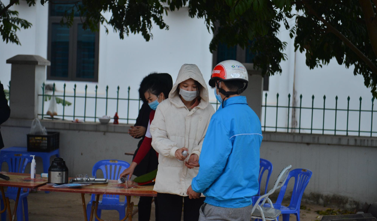 Người dân đều được đo nhiệt đo, sát khuẩn tay khi đi qua chốt kiểm soát. (Ảnh: Đinh Huy).