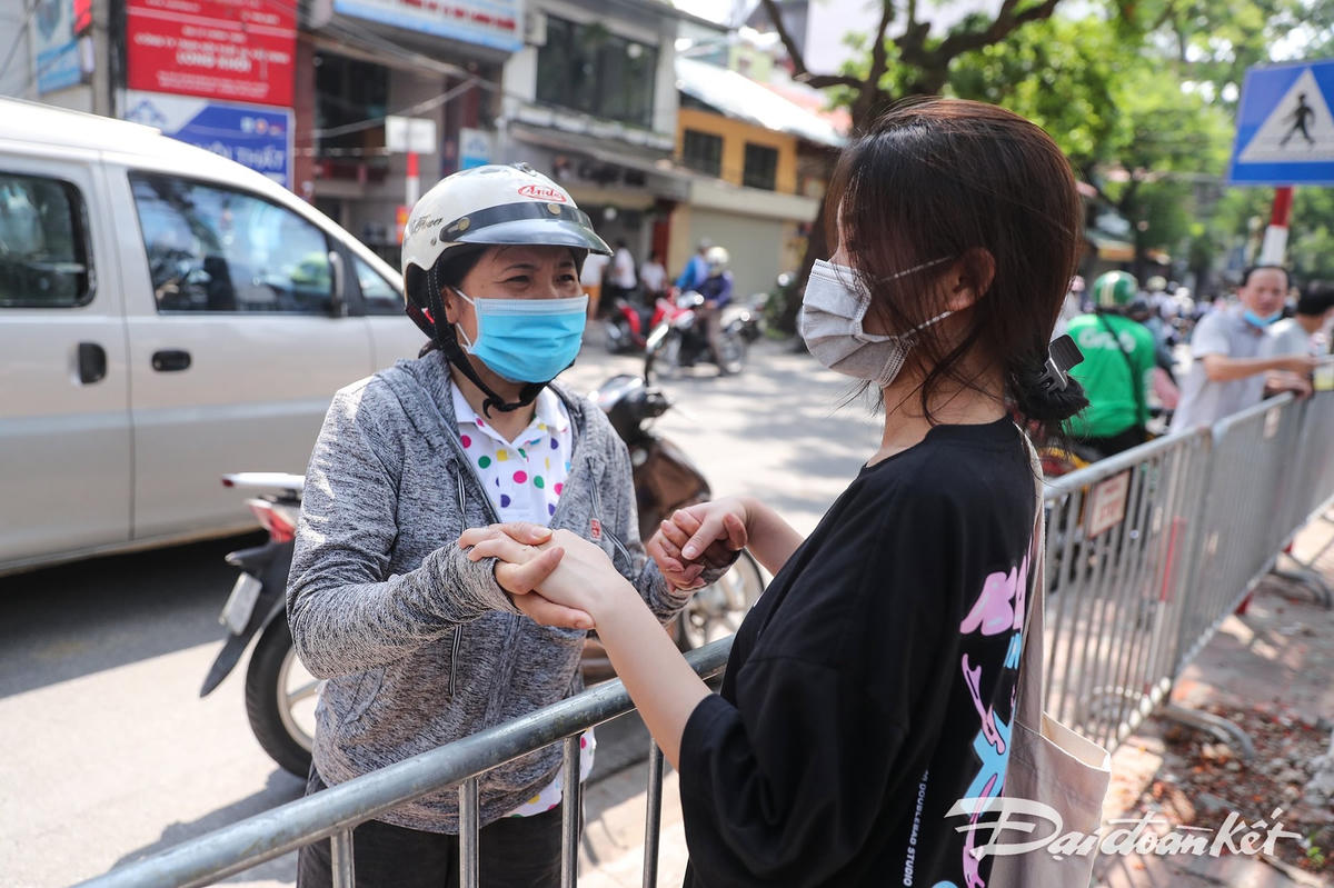 Chưa kịp chay ra xe, ngay ở hàng rào, người mẹ đã nắm lấy tay con hỏi thăm về tình hình làm bài thi. Ảnh: Quang Vinh. 