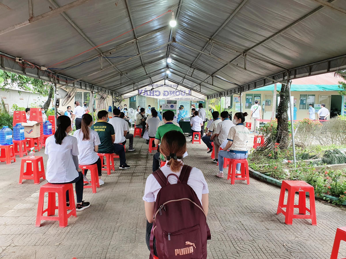Công nhân giữ khoảng cách phòng chống dịch khi đi tiêm vaccine.