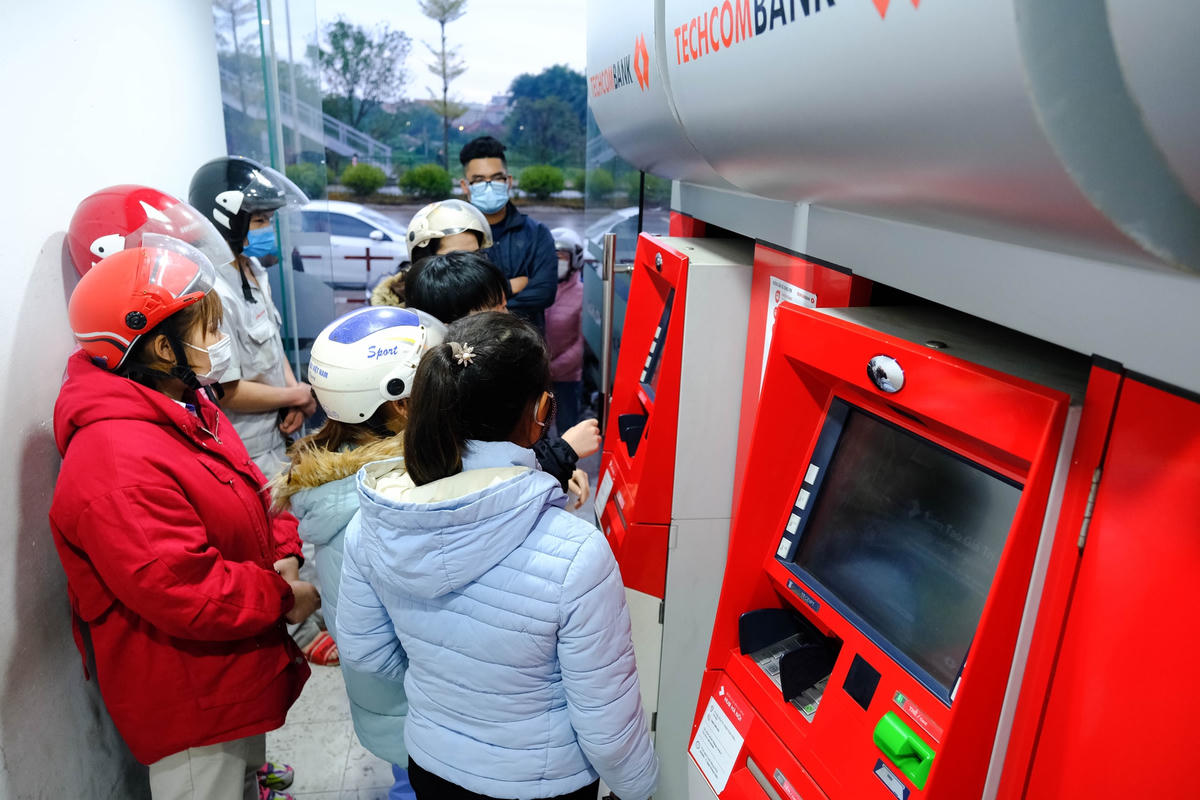 Công nhân chờ rút tiền lương tại cây ATM. Ảnh: Quang Vinh.