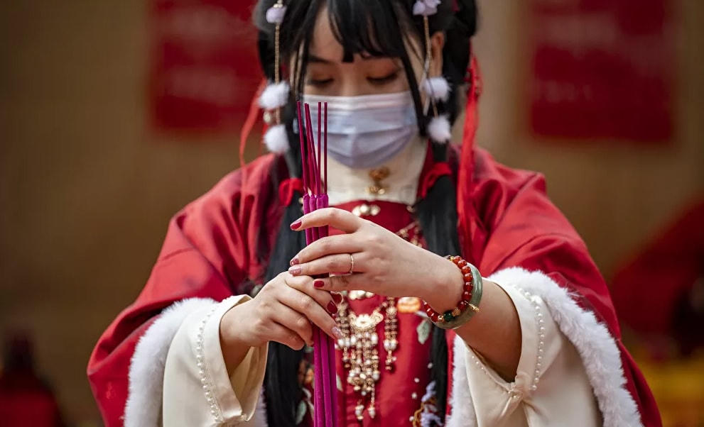 Một người phụ nữ mặc trang phục truyền thống thắp hương và cầu nguyện tại đền Ma Zhu Miao tại khu phố Tàu của Yokohama, Nhật Bản.