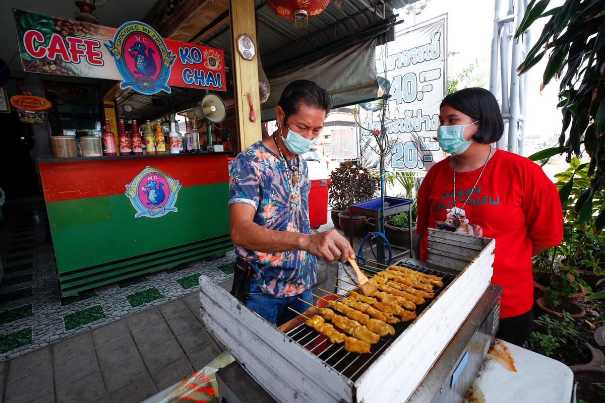 Wichai Roongtaweechai (trái) đang nướng xiên thịt cá sấu tại nhà hàng của mình. Ảnh: Diego Azubel / EPA.
