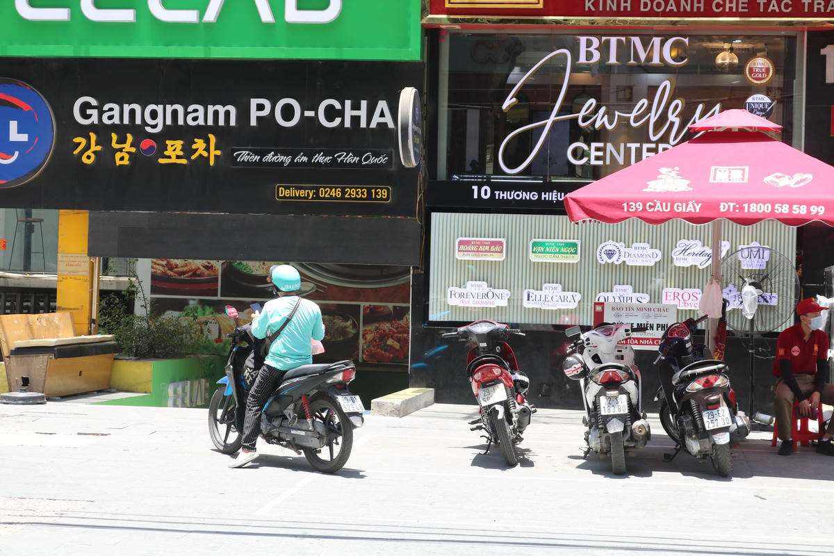 Nhiều shipper phải đứng chờ khách giữa trưa nắng để giao đồ ăn.