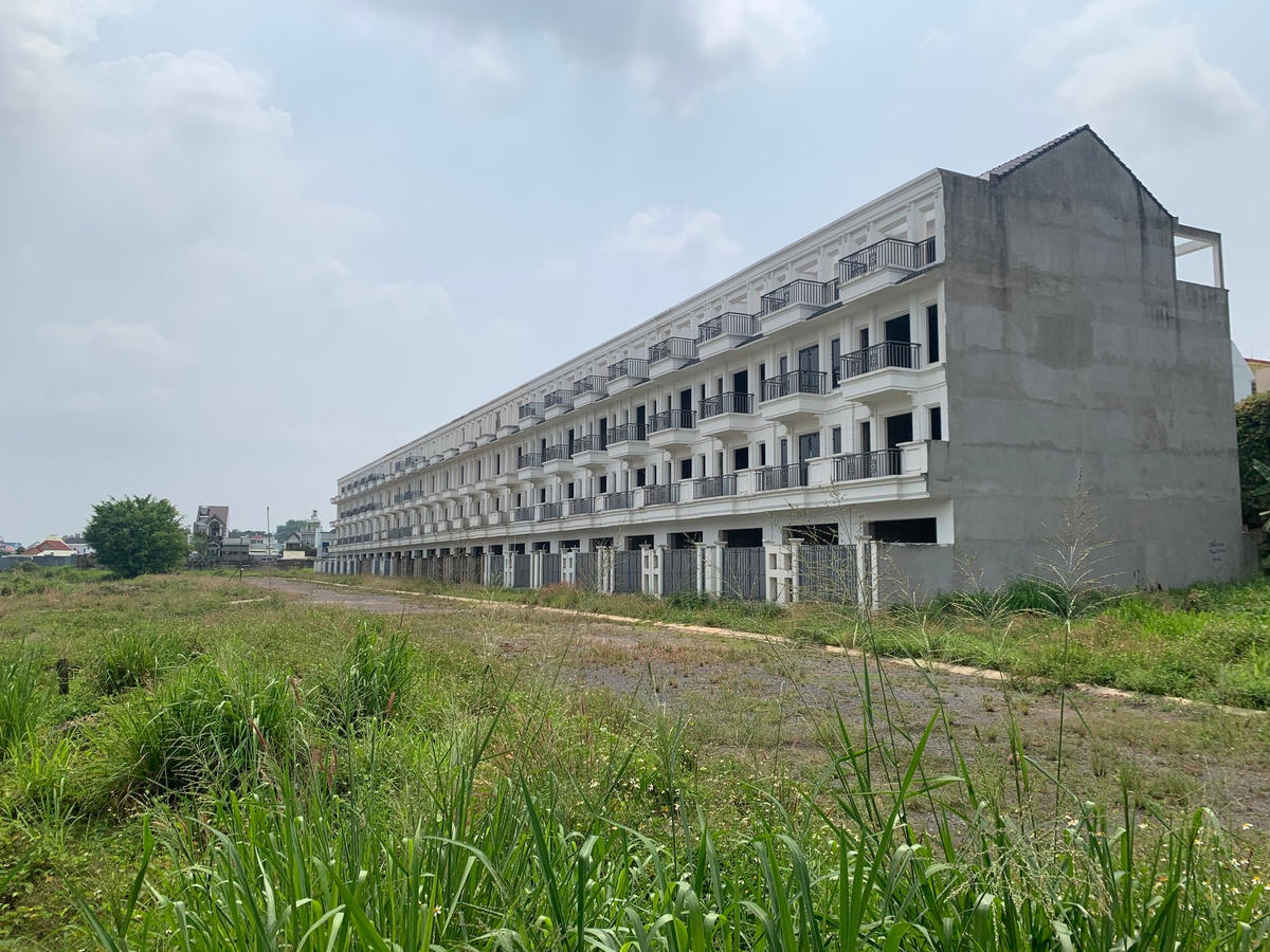 Cỏ mọc um tùm bao quanh dãy nhà phố đã gần hoàn thiện thuộc dự án KDC Bình Đa hiện đã bị ngưng xây dựng để điều tra sai phạm. (Ảnh: Mạnh Thìn)