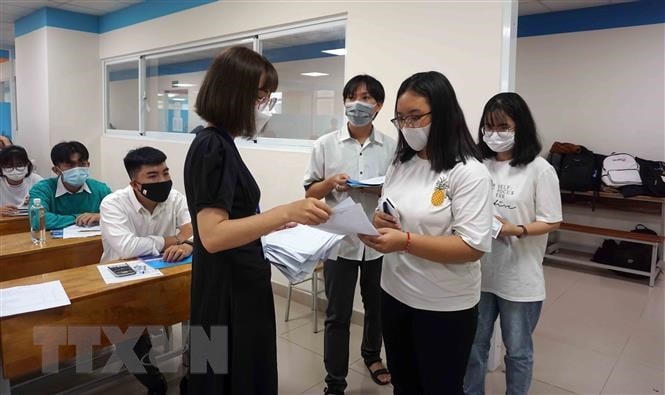 Thí sinh trình các giấy tờ và nộp bản khai báo y tế cho cán bộ coi thi tại điểm thi Trường Đại học Công nghệ TP HCM (cơ sở thành phố Thủ Đức). (Ảnh: Thu Hoài/TTXVN).