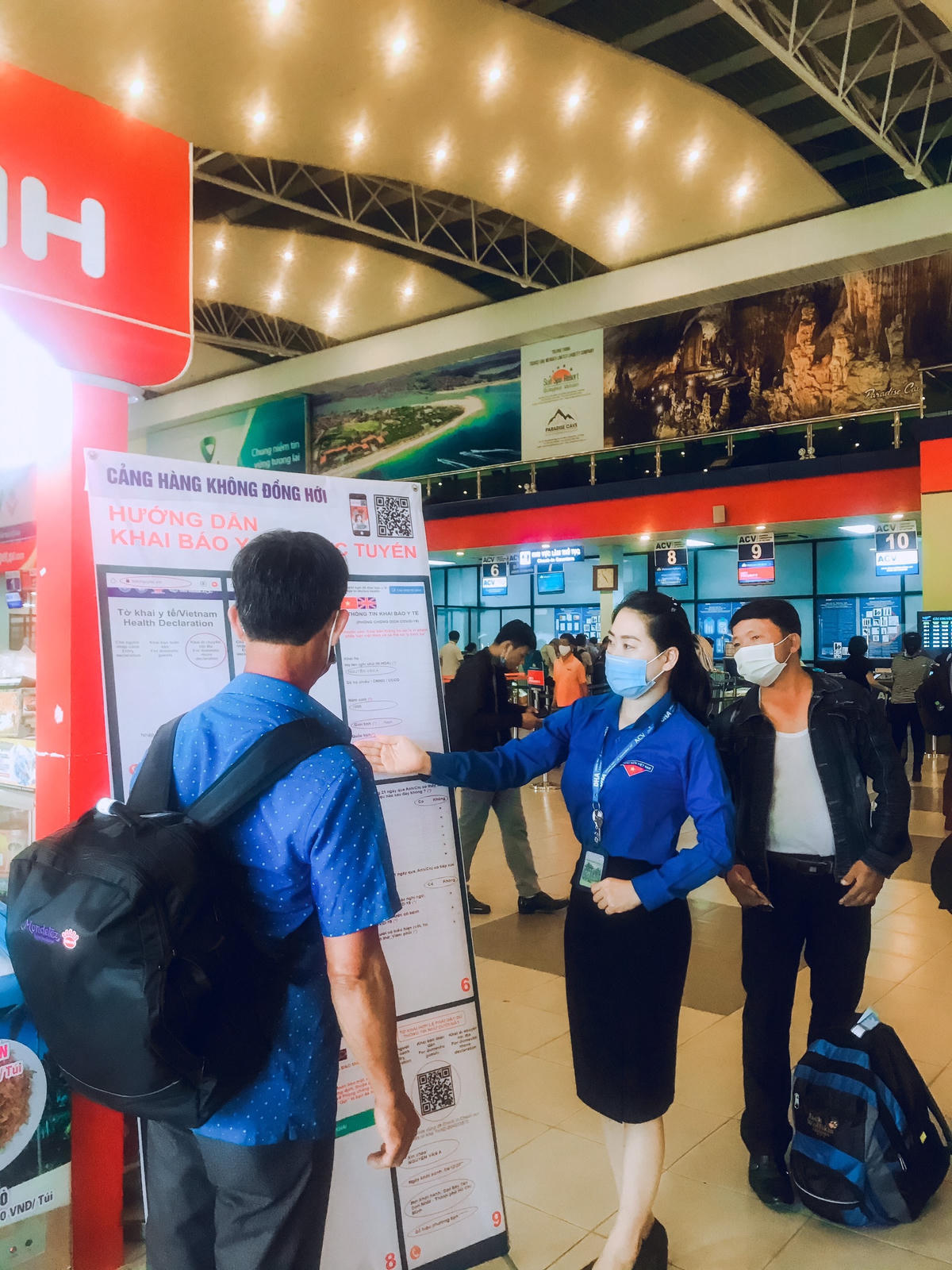Nhân viên Cảng hàng không Đồng Hới hướng dẫn hành khách về phòng chống dịch. Ảnh: Phương Chi.