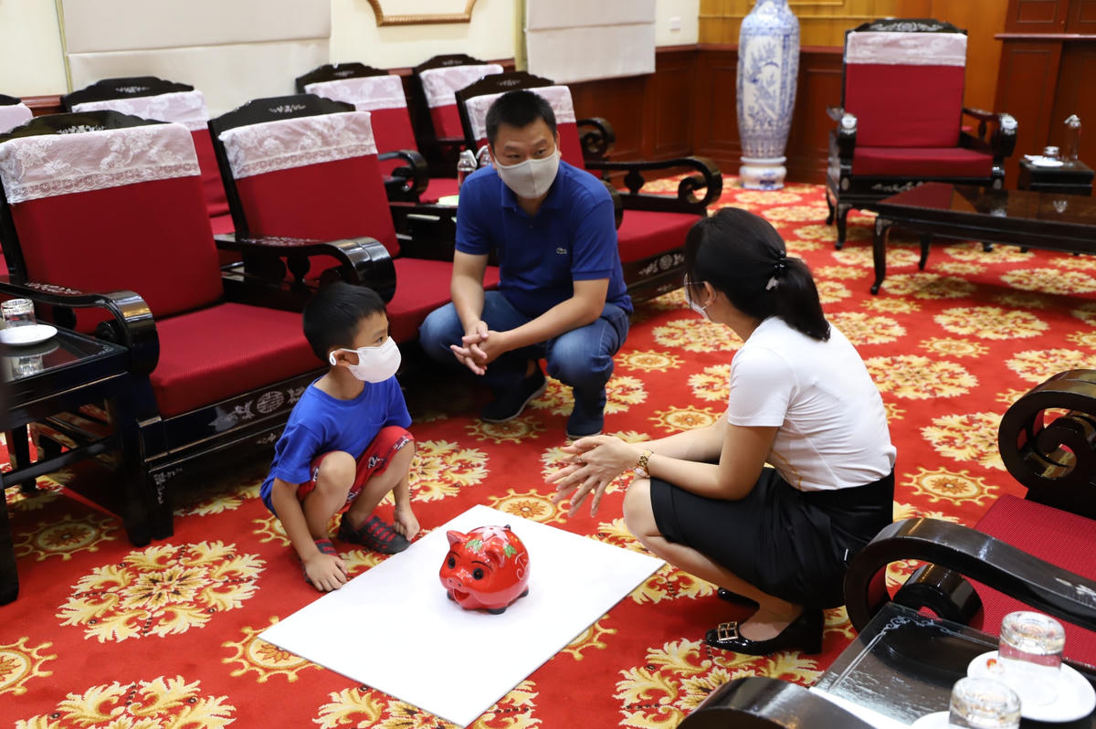 Cậu bé nhờ bố và Ban Phong trào, UBTƯ MTTQ Việt Nam- nơi tiếp nhận ủng hộ- đập lợn.