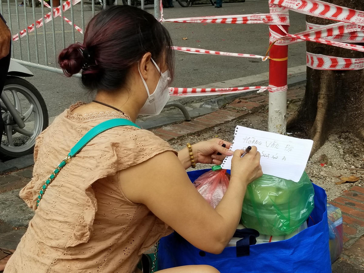 Người tiếp tế sẽ trực tiếp người bên trong khu cách ly ra nhận đồ, hoặc ghi rõ địa chỉ, số điện thoại người nhận vào những mảnh giấy.