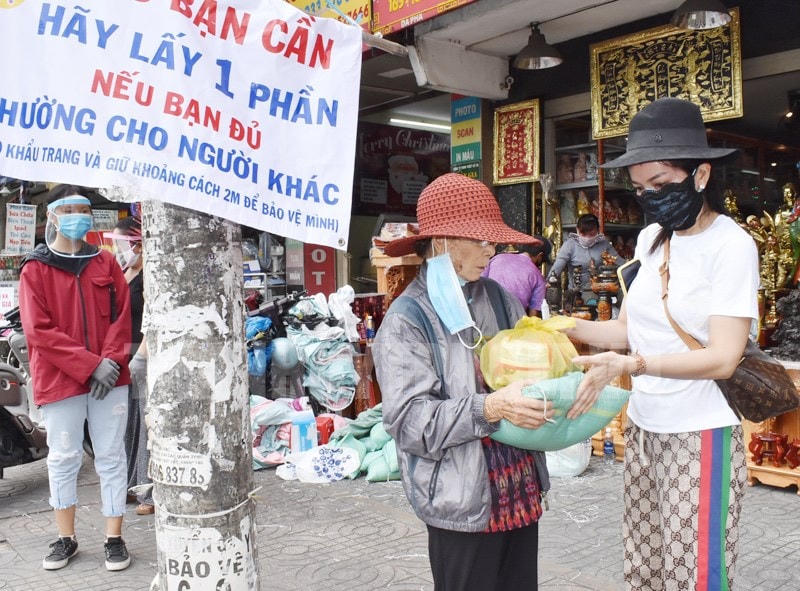 Chị Võ Thị Thùy Trang  trao gạo và cơm cho người nghèo.