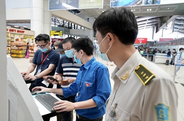 Cảng hàng không Nội Bài bố trí đội thanh niên xung kích hỗ trợ khách khai báo y tế tại 6 cây máy tính kết nối internet… để giúp hành khách hoàn thành nhanh nhất thủ tục khai báo y tế. (Ảnh: CTV/Vietnam+).