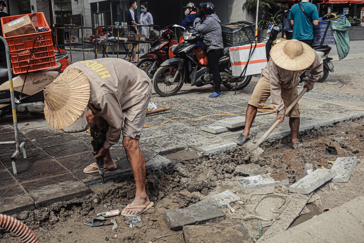 Các công nhân đang thực hiện hạng mục lát hai bên vỉa hè trên tuyến đường.