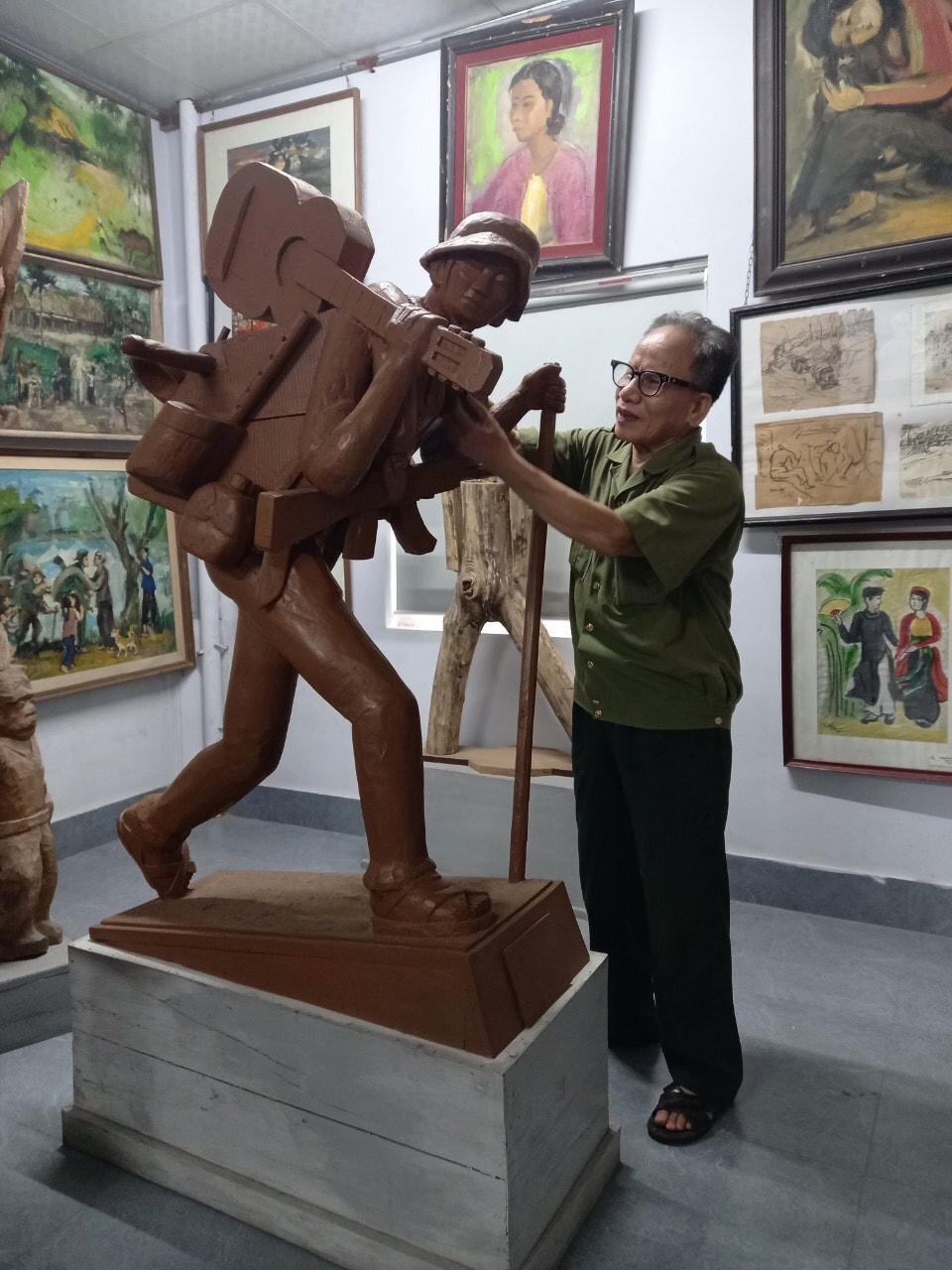 Họa sĩ Lê Duy Ứng bên tác phẩm "Bài ca ra trận"  mà ông tâm huyết.  