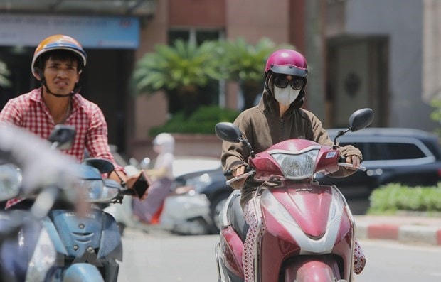 Người dân ra đường với trang phục kín mít để tránh cái nắng gay gắt. (Ảnh: TTXVN).