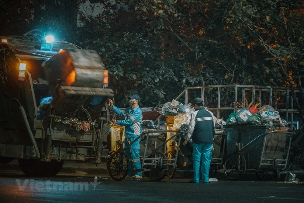 Gió mùa Đông Bắc về trong đêm, trời mưa, nhiệt độ đột ngột hạ xuống mức 10-15 độ C, trong khi nhiều người dân đã chìm sâu vào giấc ngủ thì không ít người lao động bán hàng rong, lao công lại tấp nập làm việc. (Ảnh: Minh Hiếu/Vietnam+).