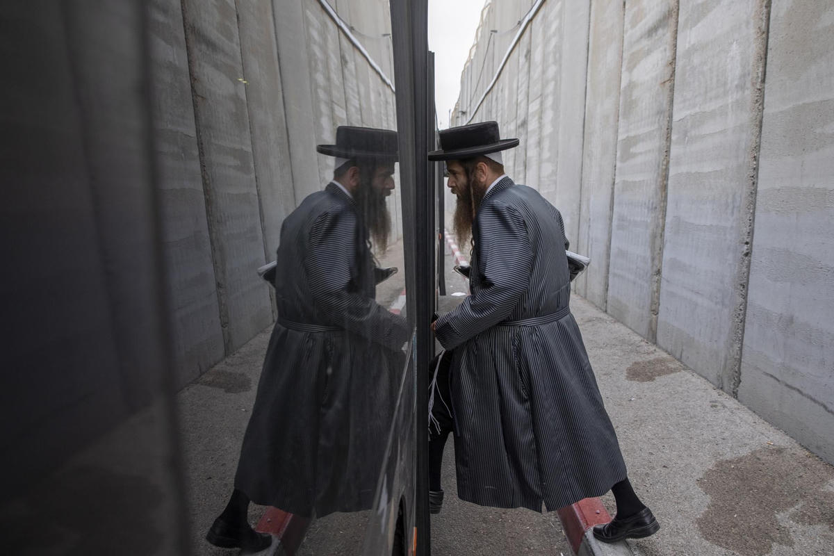 Một người đàn ông Do Thái Chính thống giáo bước lên xe buýt gần hàng rào bê tông do Israel xây dựng để bảo vệ Lăng mộ của Rachel, ngôi đền linh thiêng thứ ba của Do Thái giáo, trong một buổi cầu nguyện hàng năm thu hút hàng chục nghìn người thờ cúng để tưởng nhớ Đức Thánh tổ Do Thái Rachel, ở thị trấn bờ tây của thành phố Bethlehem, Pennsylvania. Ảnh: AP/Oded Balilty.