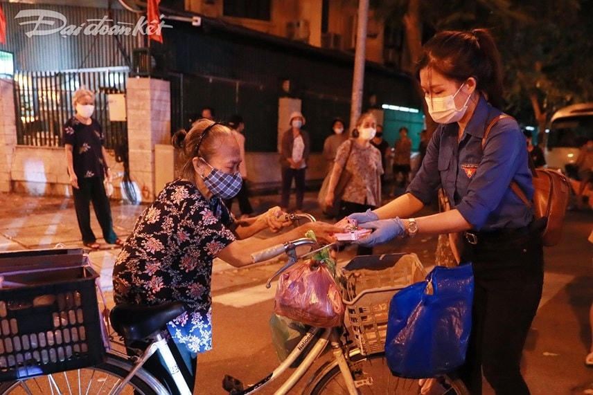 Điểm đến tiếp theo của đoàn dừng tại phố Trần Bình Trọng. Từng cụ già, bà bầu hay những người có hoàn cảnh khó khăn xếp hàng nhận từng suất ăn. Ảnh: Quang Vinh.   