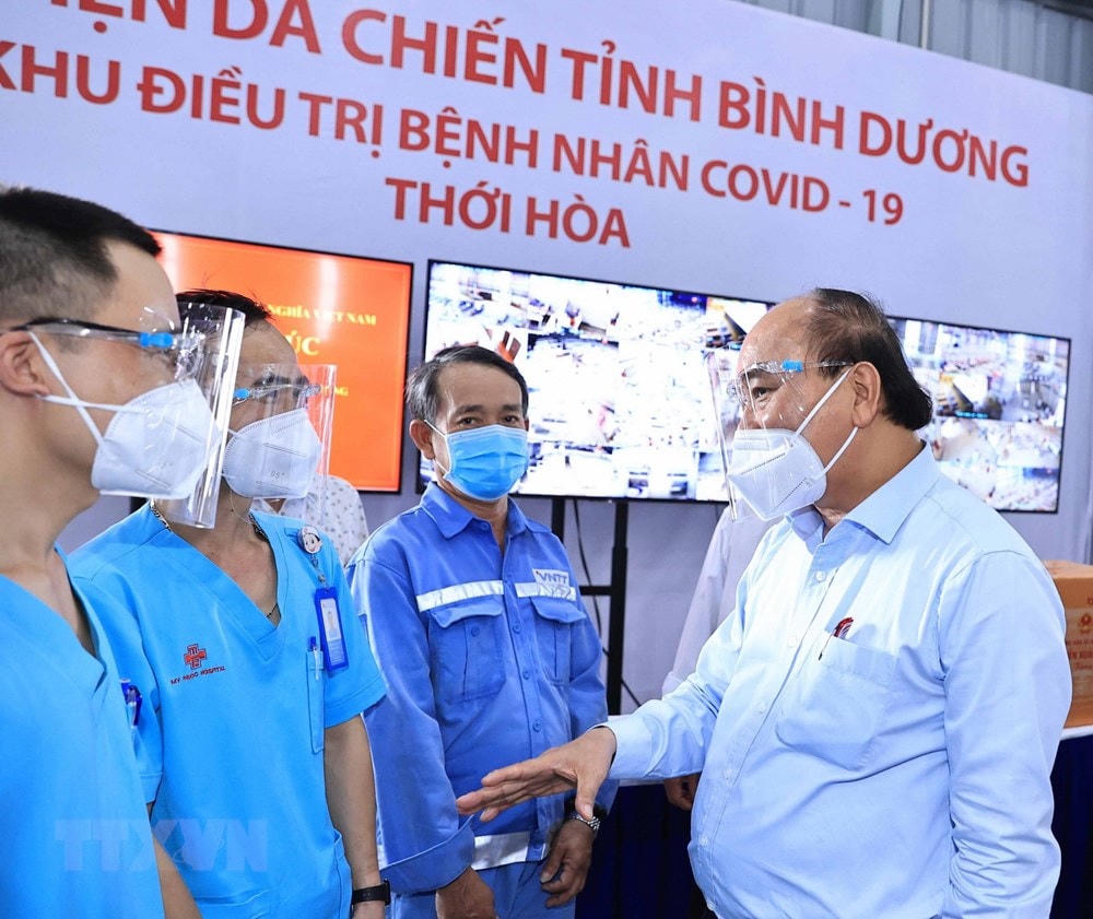 Chủ tịch nước Nguyễn Xuân Phúc thăm hỏi, động viên đội ngũ cán bộ, nhân viên y tế điều trị bệnh nhân Covid-19. (Ảnh: Thống Nhất/TTXVN).