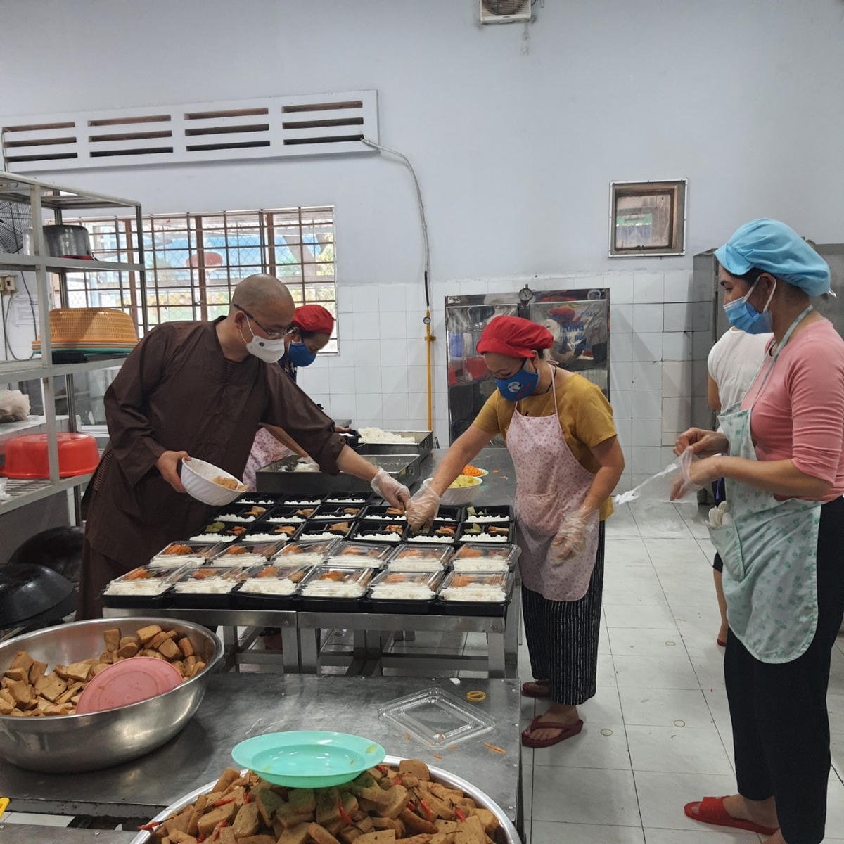 Đại đức Thích Minh Đạo cùng các đầu bếp cho cơm và thức ăn vào hộp. Ảnh: Phương Chi.