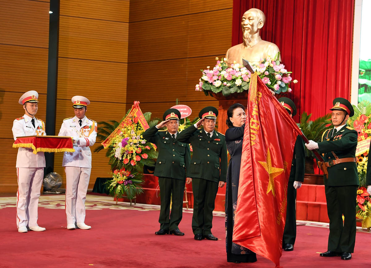 Chủ tịch Chủ tịch Quốc hội Nguyễn Thị Kim Ngân gắn Huân chương Độc lập hạng Ba lên Quân kỳ quyết thắng của báo Quân đội nhân dân. Ảnh: Trọng Hải.