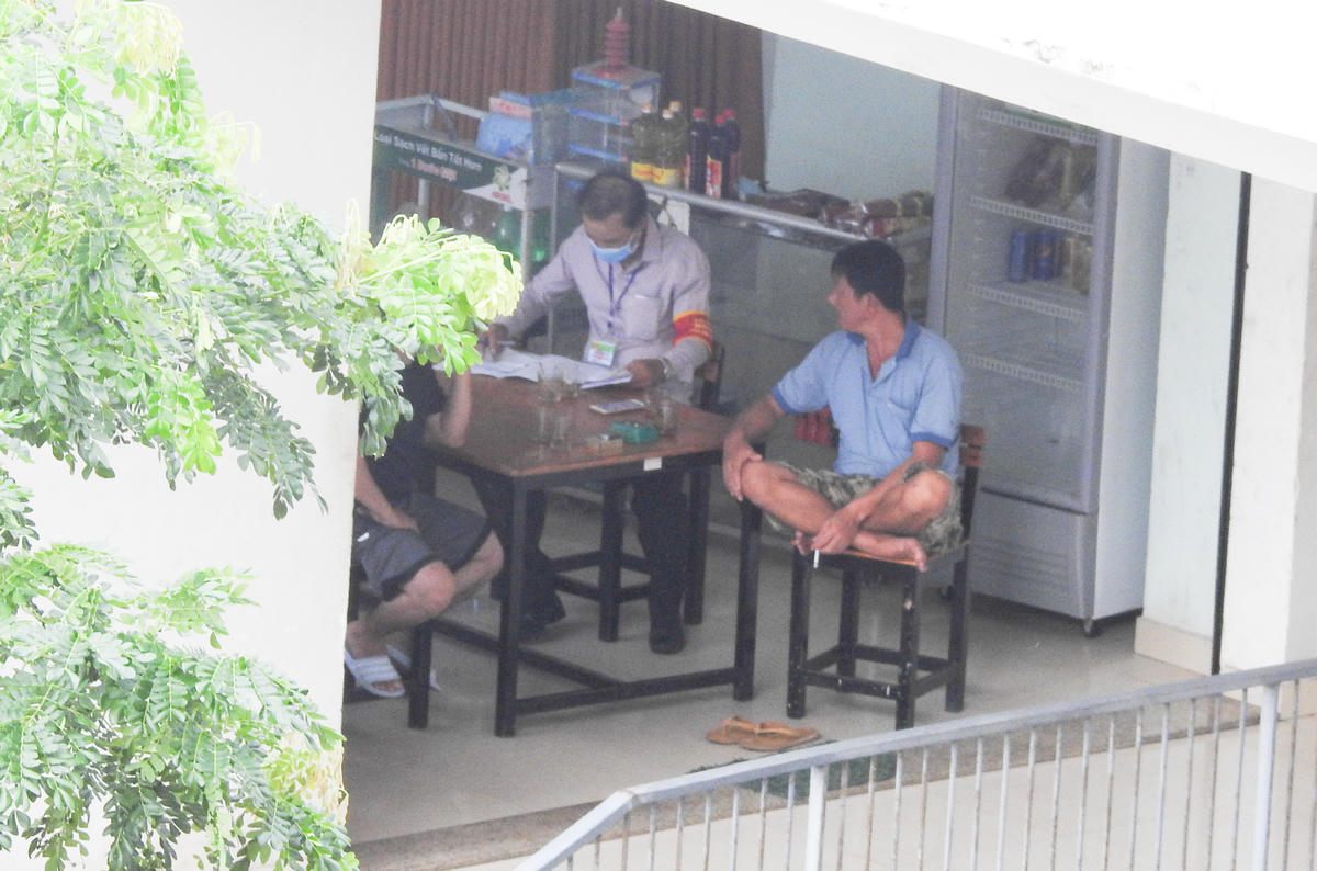 Ông Phúc không đeo khẩu trang, ngồi hút thuốc ở tư thế không nghiêm túc khi trao đổi công việc với cán bộ tổ dân phố. (Ảnh chụp sáng 30/8).