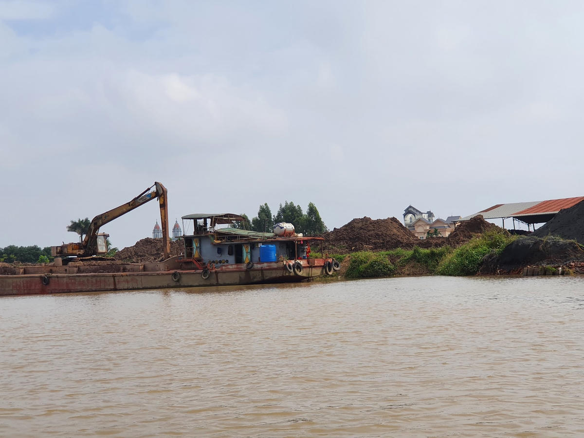 Đất được đưa từ thuyền lên sát mép sông.