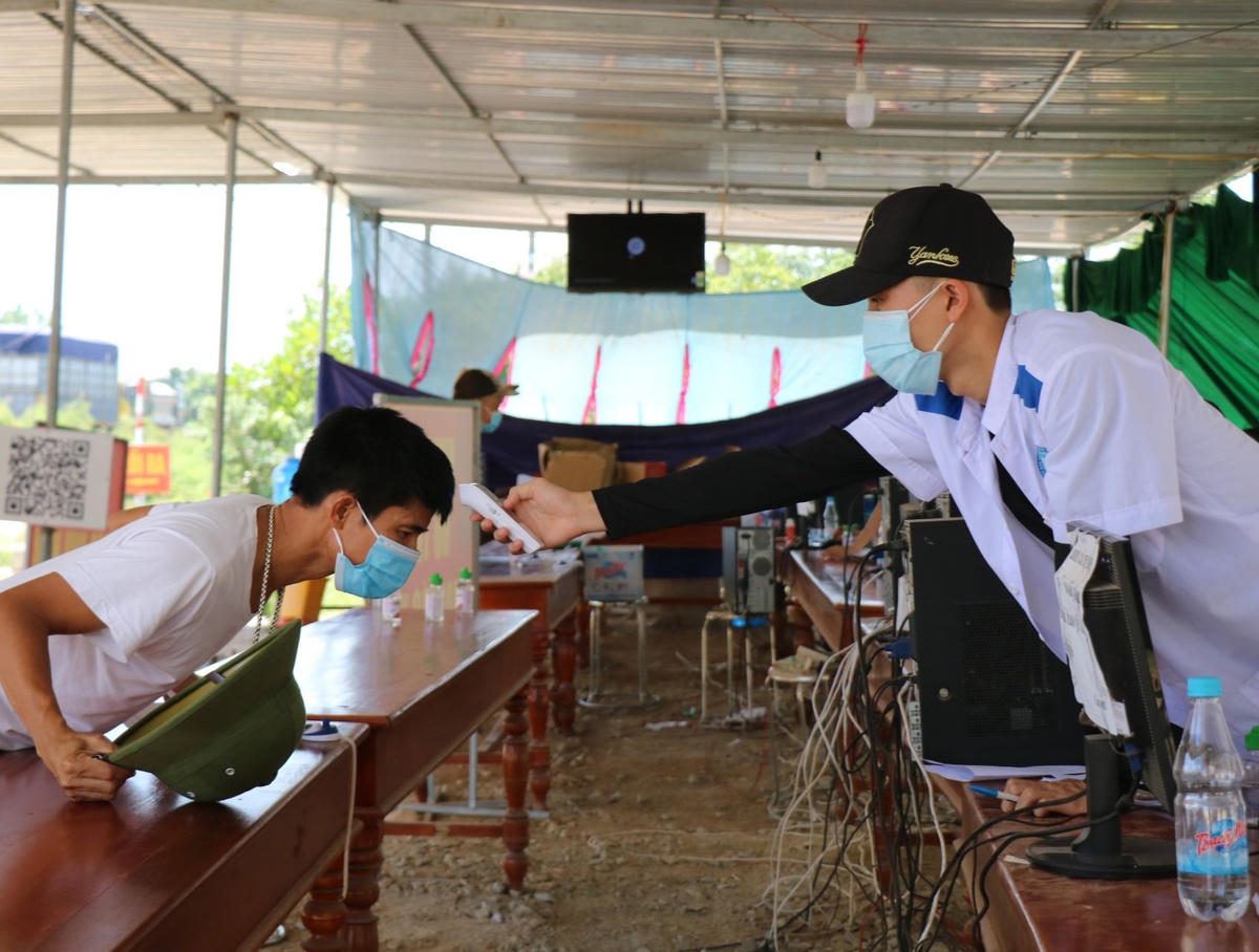 Bạn Trần Lý Quang tiến hành đo thân nhiệt cho tài xế khi vào khai báo y tế tại chốt kiểm soát.