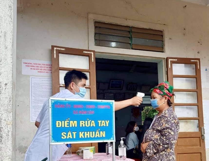 Người dân xã Nậm Càn, huyện Kỳ Sơn kiểm tra nhiệt độ, rửa tay sát khuẩn trước khi vào bỏ phiếu.