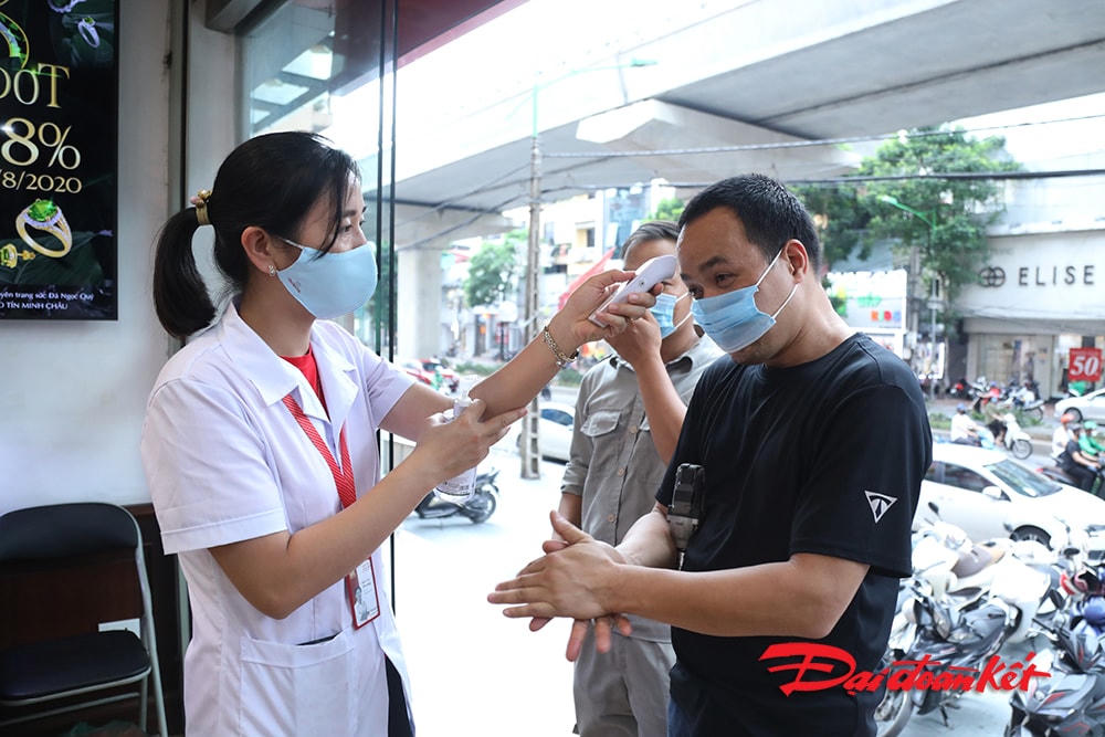 Người dân đến giao dịch tại cửa hàng được phát khẩu trang, rửa tay sát khuẩn và đo thân nhiệt.