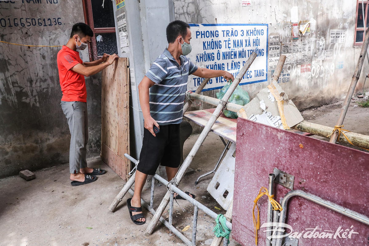 Đây là một trong những khu vực lập chốt "khóa cứng" tại thị trấn Yên Mỹ. Người dân gửi đồ vào bên trong chỉ để tại bàn, sau đó người nhà sẽ ra nhận, tránh tiếp xúc gần. Ảnh: Quang Vinh. 