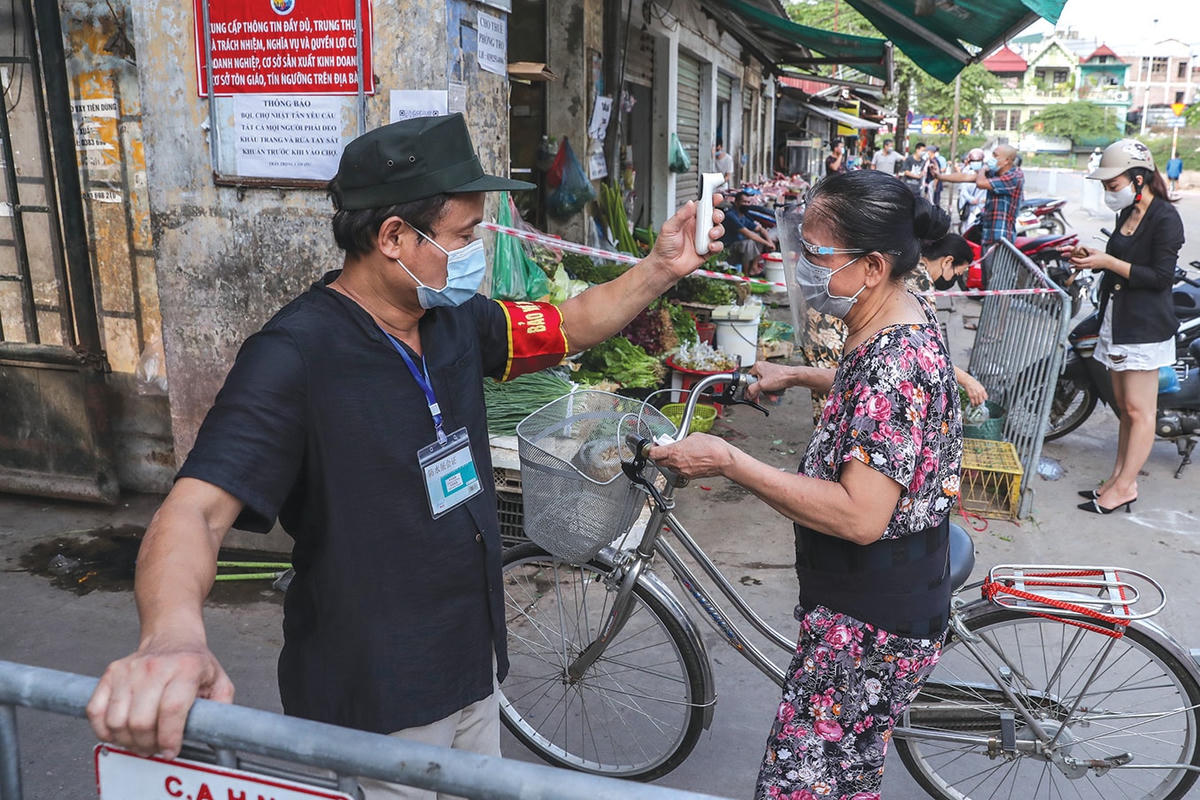 Đo thân nhiệt trước khi vào chợ.