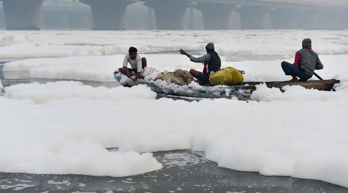 Các ngư dân cố gắng đi qua lớp bọt độc hại nổi trên sông Yamuna. Ảnh: indianexpress.com.