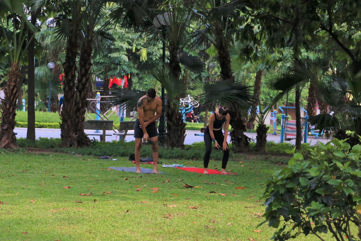 Cặp đôi trải thảm tập Yoga trong công viên.