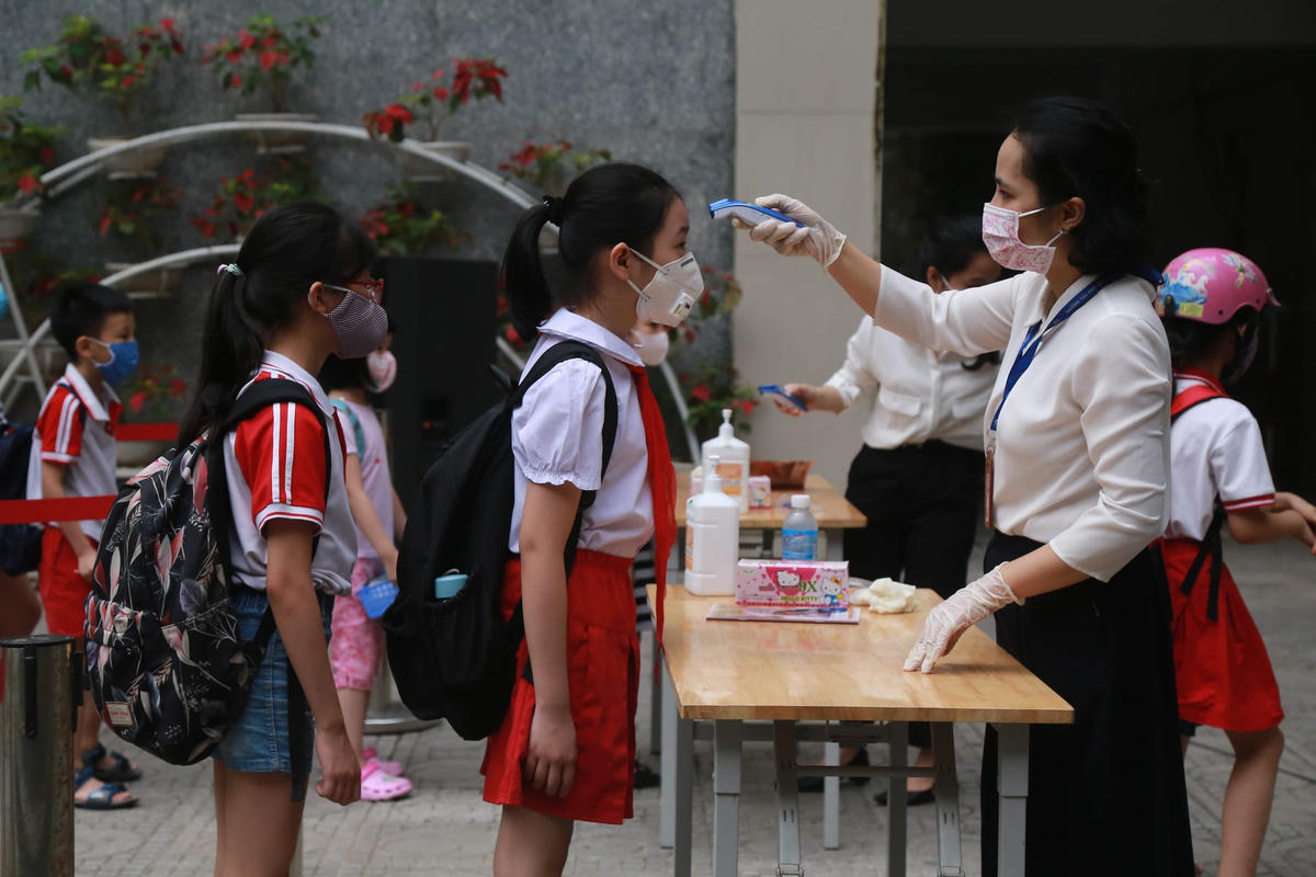 Đo thân nhiệt cho học sinh trước khi vào lớp hồi tháng tháng 4 tại Trường Tiểu học Dịch Vọng, quận Cầu Giấy, Hà Nội. Ảnh: Quang Vinh.  