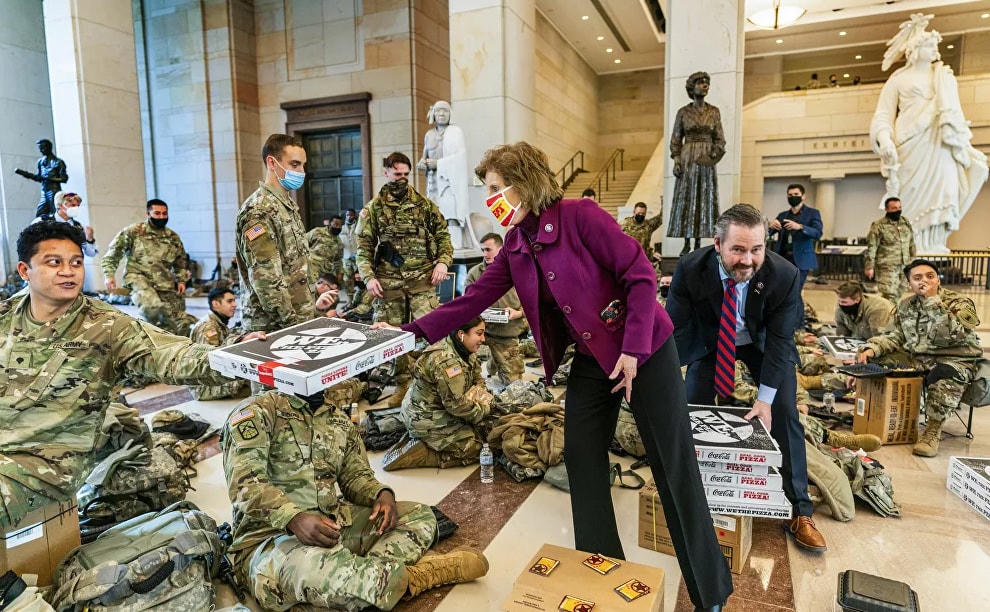 Các Hạ nghị sĩ Vicky Hartzler và Michael Waltz đưa pizza cho các thành viên của Lực lượng Vệ binh Quốc gia tập trung tại sảnh dành cho khách tại Điện Capitol, khi Hạ viện tiếp tục với cuộc bỏ phiếu gấp gáp để luận tội Tổng thống Donald Trump.  