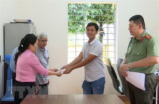 Bà Trần Thị Thanh Phượng, đại diện cho những người nhặt được tiền, trao trả số tiền cho anh Lê Hồng Phong. (Ảnh: Đậu Tất Thành/TTXVN).