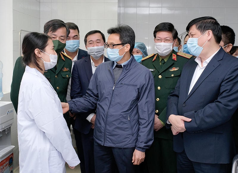 Phó Thủ tướng Vũ Đức Đam và Bộ trưởng Bộ Y tế Nguyễn Thanh Long trò chuyện với một nữ tình nguyện viên tiêm vaccine Covid-19.