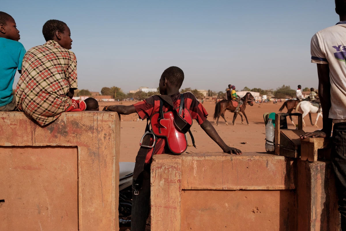 Tay đua trẻ đang đợi đến lượt đua. Các tay đua trẻ được chủ ngựa trả tiền, hỗ trợ và cung cấp các thiết bị phù hợp để tập luyện và đua tranh. Ảnh: Guy Peterson / The Guardian.