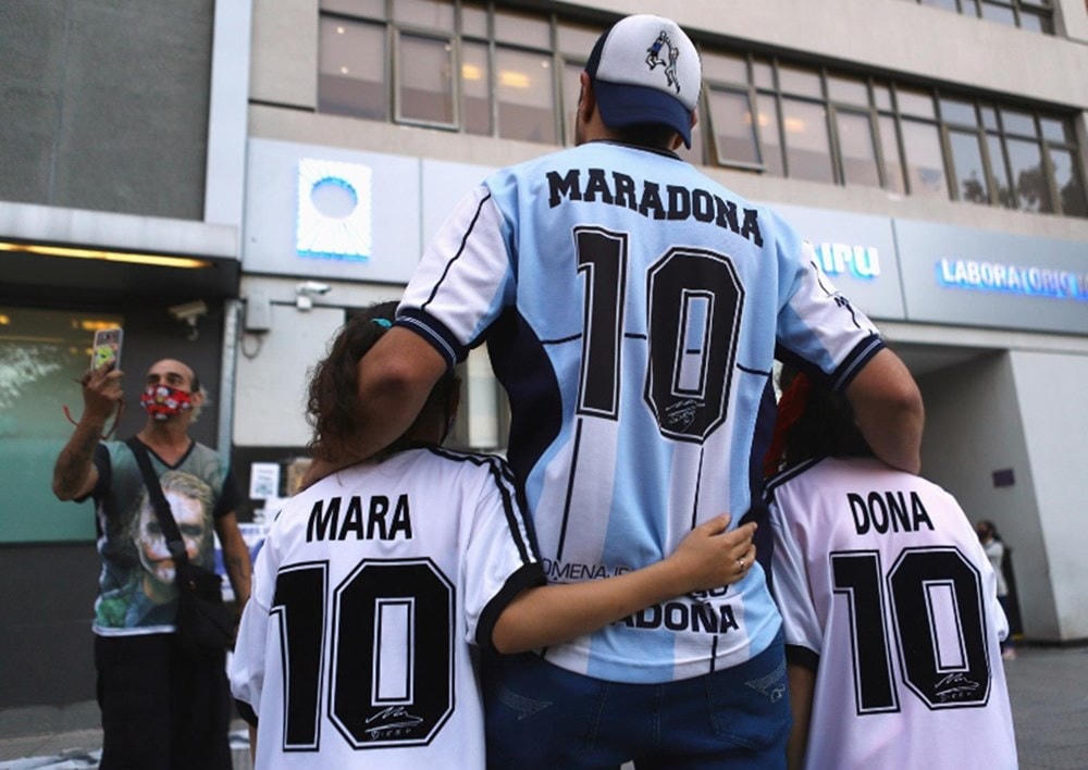 Cổ động viên Walter Rotundo chụp ảnh cùng 2 con gái song sinh Mara và Dona bên ngoài bệnh viện nơi Diego Maradona thực hiện ca phẫu thuật não ở Buenos Aires. (Ảnh: Reuters).