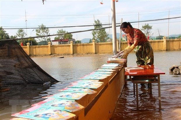 Giáo viên trường Tiểu học Thạch Tân (Xã Tân Lâm Hương, Thạch Hà) phơi sách cho học trò. Ảnh: Hoàng Ngà/TTXVN.  