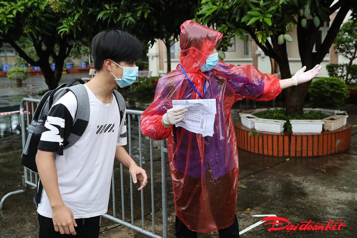 Trời ngớt mưa, lực lượng tình nguyện đứng phân làn hướng dẫn thí sinh vào phòng thi. Ảnh: Quang Vinh.