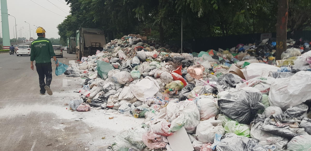 Công nhân môi trường rải vôi lên đống rác thải để hạn chế mùi hôi thối.