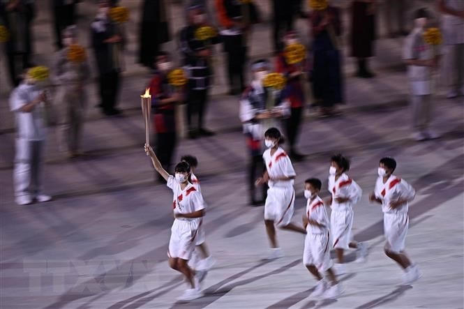 Các vận động viên rước đuốc Olympic tại lễ khai mạc Olympic Tokyo 2020 ở Tokyo, Nhật Bản, ngày 23/7. (Ảnh: AFP/TTXVN).