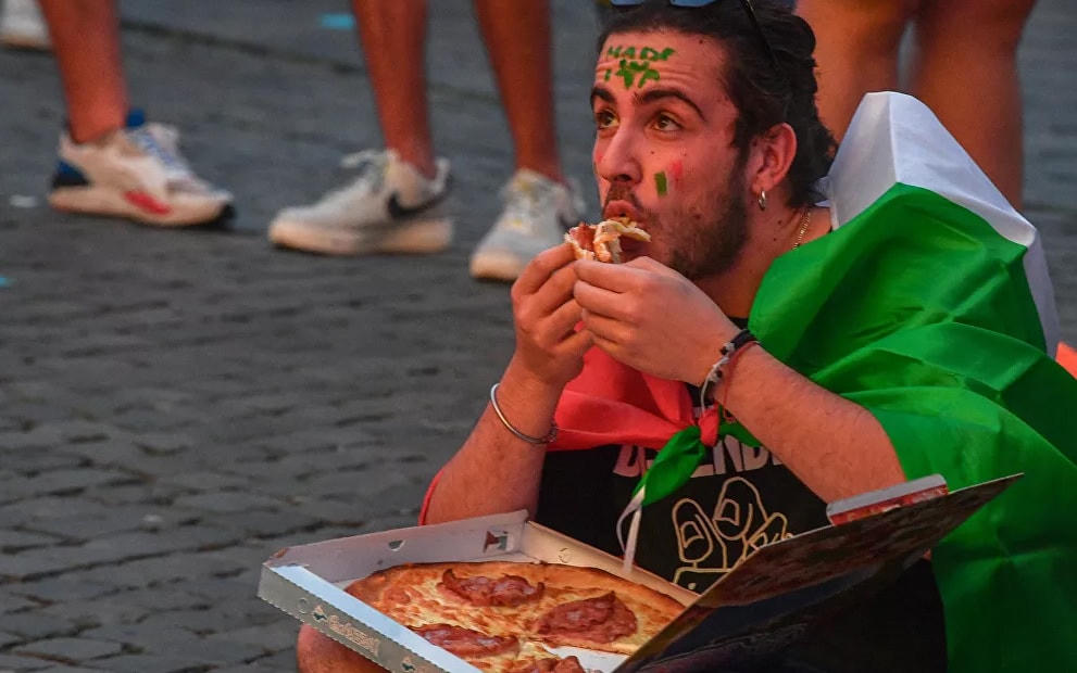 Một cổ động viên Ý ăn pizza tại khu vực dành cho người hâm mộ trên quảng trường Piazza del Popolo ở Rome.